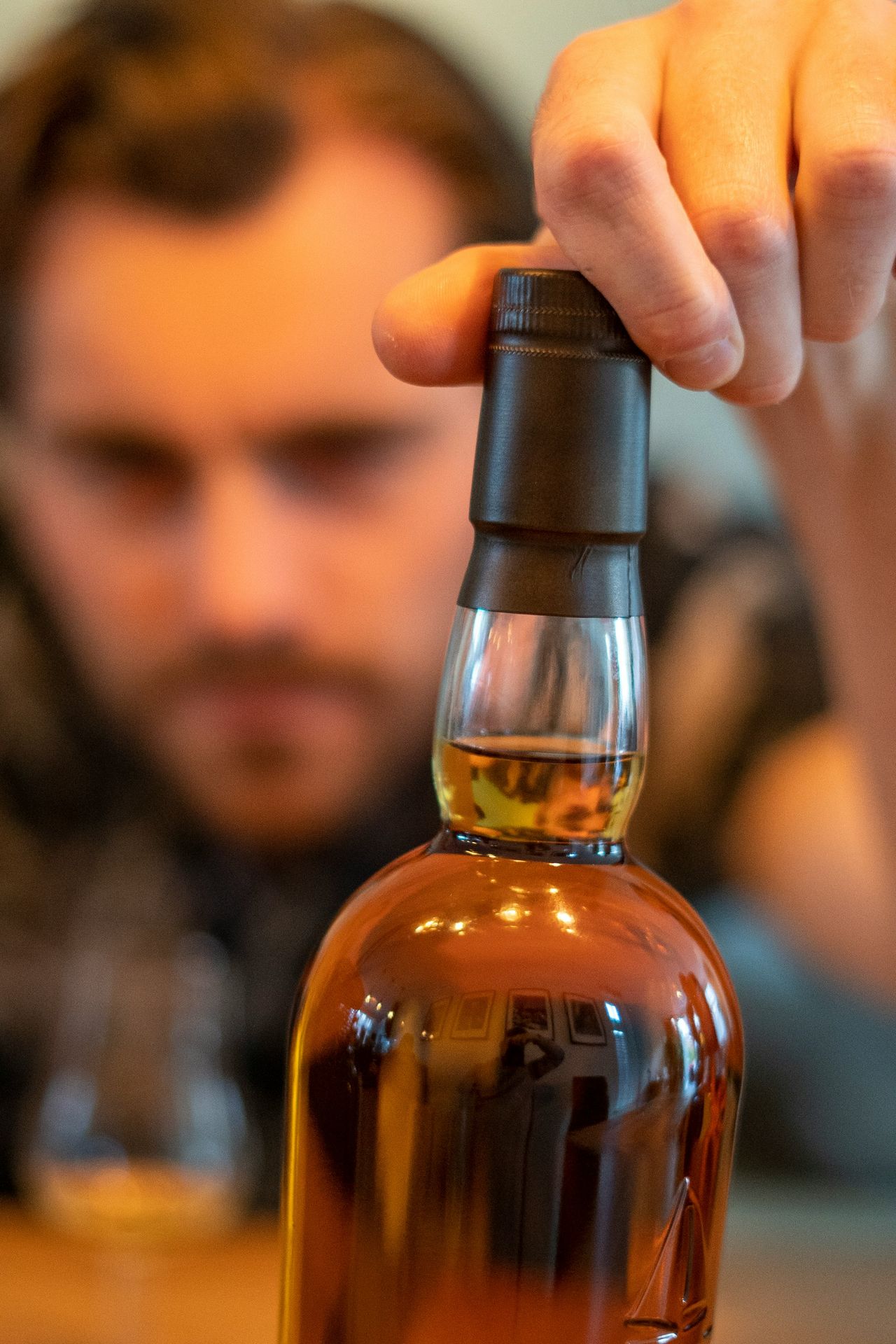 person holding clear glass bottle